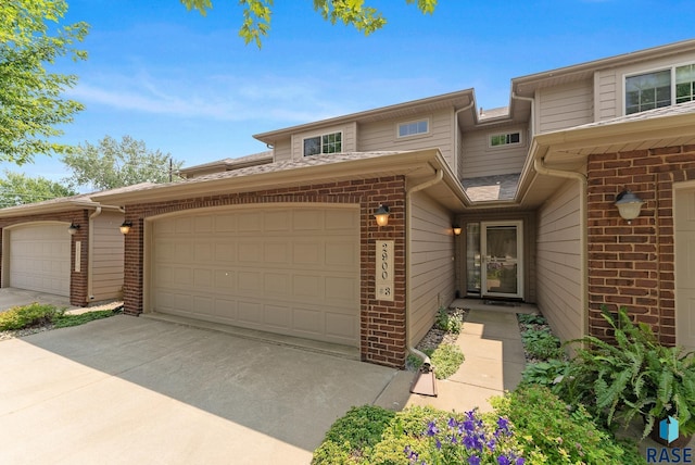 view of front of property featuring a garage, driveway, and brick siding