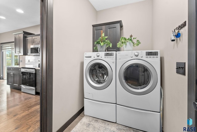 laundry room with baseboards, cabinet space, washer and clothes dryer, and light wood finished floors