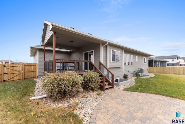 back of property with a deck, a yard, fence, and a gate