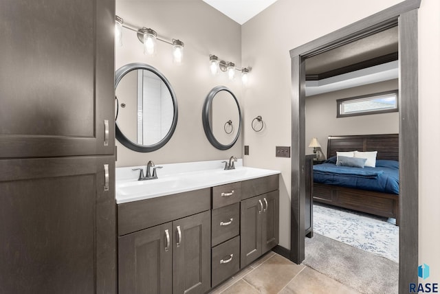 bathroom with ensuite bathroom, double vanity, a sink, and tile patterned floors