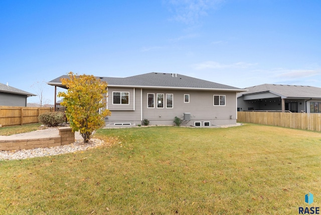 rear view of property featuring central air condition unit, fence, and a lawn