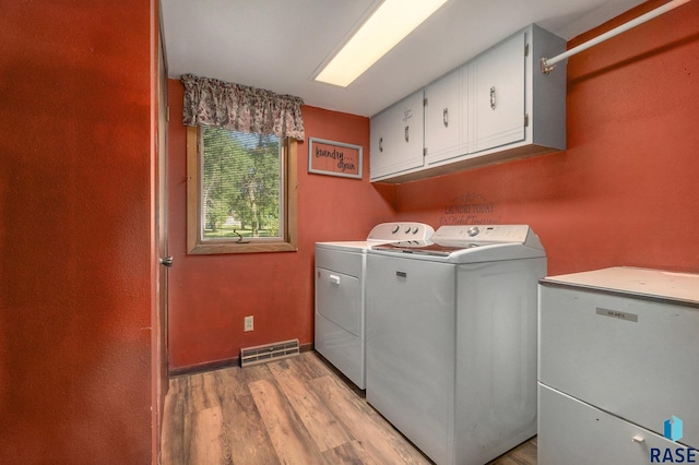 laundry room featuring visible vents, baseboards, light wood-type flooring, cabinet space, and washing machine and clothes dryer