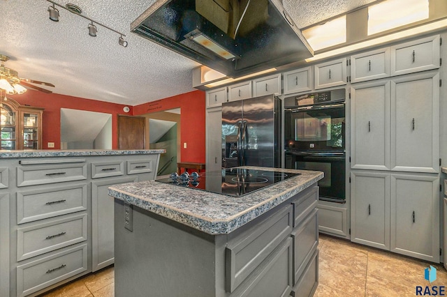 kitchen featuring black appliances, a kitchen island, gray cabinets, and exhaust hood