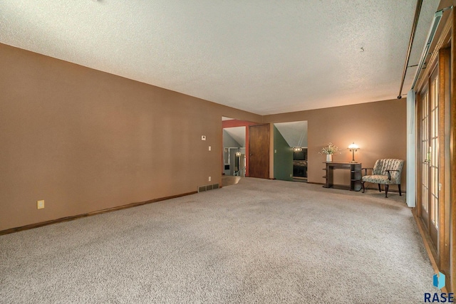 spare room featuring baseboards, a textured ceiling, visible vents, and carpet flooring