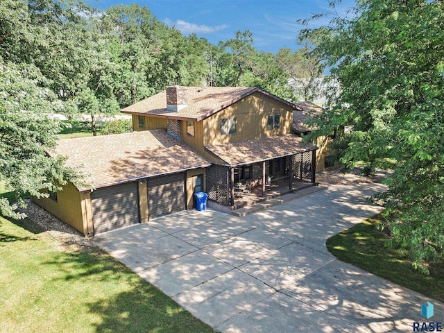 view of front of property with a garage, a shingled roof, concrete driveway, a chimney, and a porch