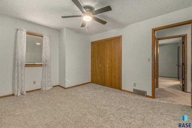 unfurnished bedroom featuring light carpet, a closet, visible vents, and a textured ceiling