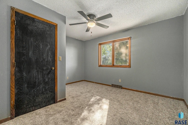 unfurnished room with visible vents, a ceiling fan, carpet flooring, a textured ceiling, and baseboards