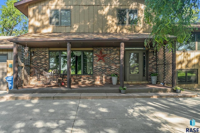 doorway to property featuring a patio and brick siding