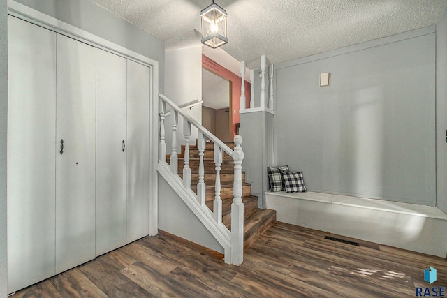 stairs featuring a textured ceiling and wood finished floors