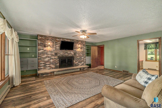 living area with a textured ceiling, visible vents, baseboard heating, a brick fireplace, and dark wood-style floors