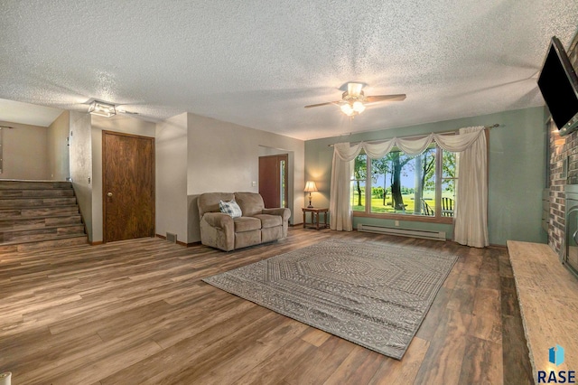 unfurnished living room featuring stairs, a fireplace, baseboard heating, and wood finished floors