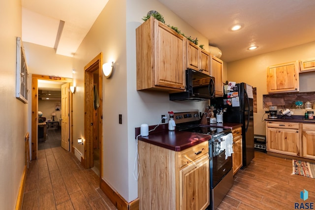 kitchen with baseboards, dark countertops, dark wood-type flooring, black appliances, and recessed lighting