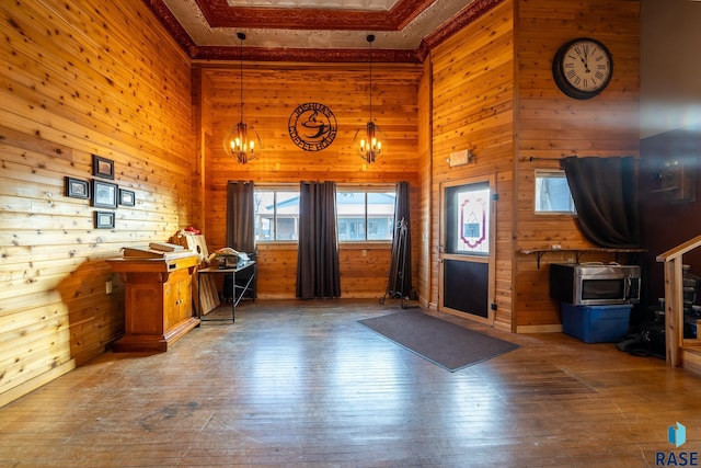 unfurnished office featuring an inviting chandelier, wood walls, a high ceiling, and wood finished floors