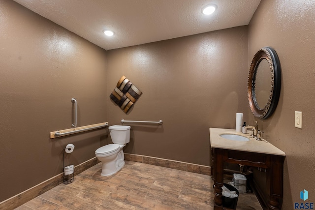 half bath with baseboards, toilet, wood finished floors, vanity, and recessed lighting