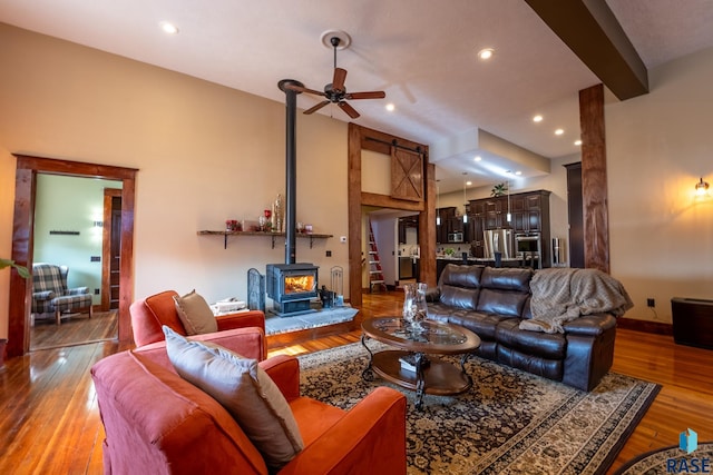 living room featuring a ceiling fan, recessed lighting, a wood stove, and wood finished floors