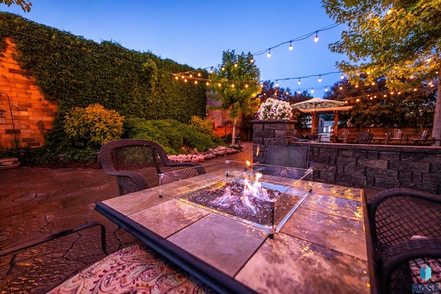 patio terrace at dusk featuring fence and a fire pit