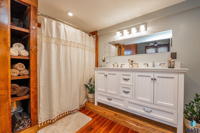 full bath featuring double vanity, a sink, and wood finished floors