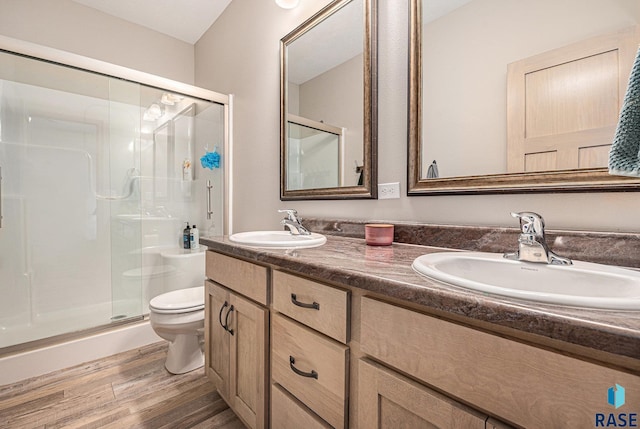 full bath with wood finished floors, a sink, toilet, and a shower stall