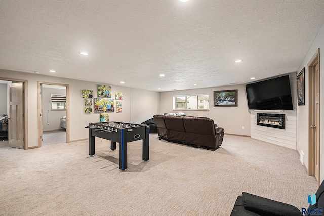 game room with light carpet, a textured ceiling, a glass covered fireplace, and recessed lighting