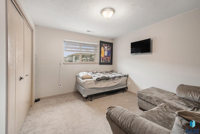 bedroom with light carpet, a textured ceiling, visible vents, and baseboards