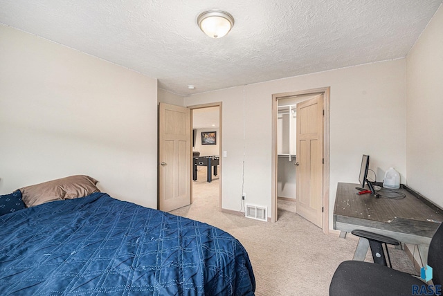 bedroom with light carpet, a textured ceiling, and visible vents