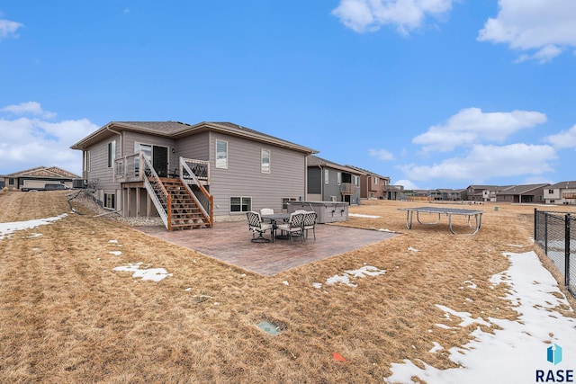 back of property with a residential view, stairs, a trampoline, fence, and a patio area