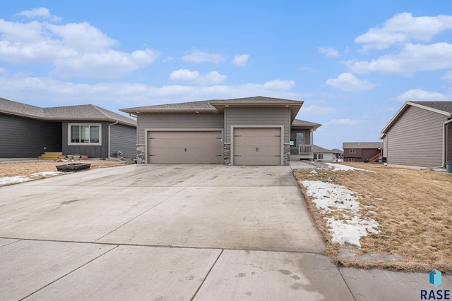 view of front of property featuring a garage, stone siding, and driveway