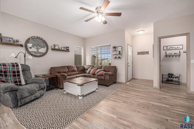 living room with light wood finished floors, a ceiling fan, and baseboards