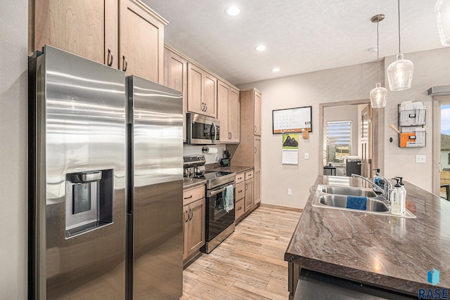 kitchen featuring light wood-style flooring, recessed lighting, a sink, hanging light fixtures, and appliances with stainless steel finishes