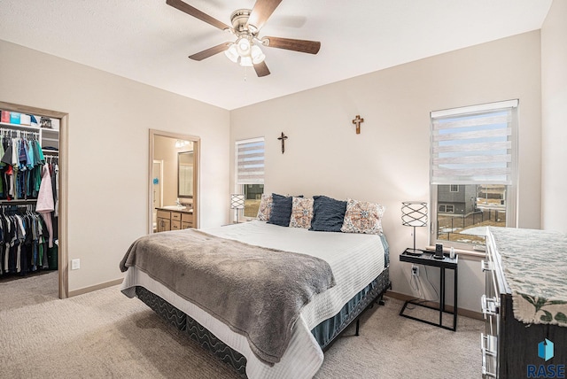 bedroom featuring a closet, multiple windows, a walk in closet, and baseboards