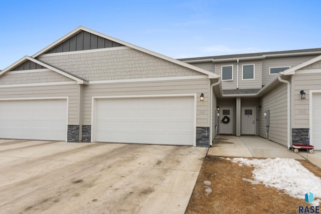 view of front of home featuring stone siding, an attached garage, and concrete driveway