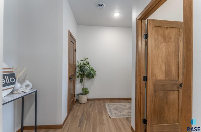 hall with light wood-type flooring and baseboards