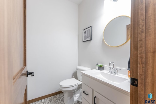 half bath with toilet, baseboards, and vanity