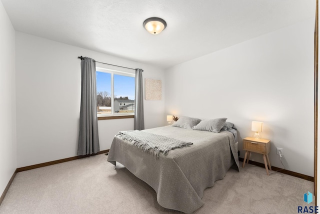 bedroom with baseboards and light colored carpet