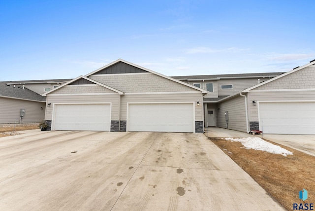 view of front facade featuring an attached garage, stone siding, board and batten siding, and concrete driveway