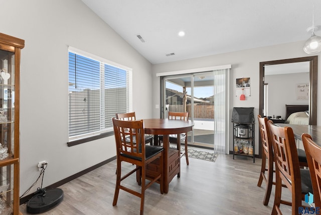 dining room featuring visible vents, vaulted ceiling, baseboards, and wood finished floors