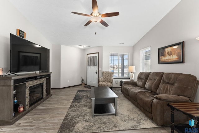 living room featuring lofted ceiling, visible vents, baseboards, and wood finished floors