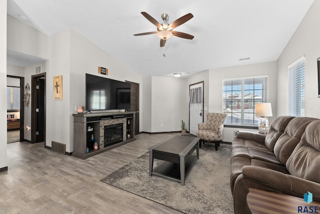 living room with lofted ceiling, light wood finished floors, a fireplace, and visible vents