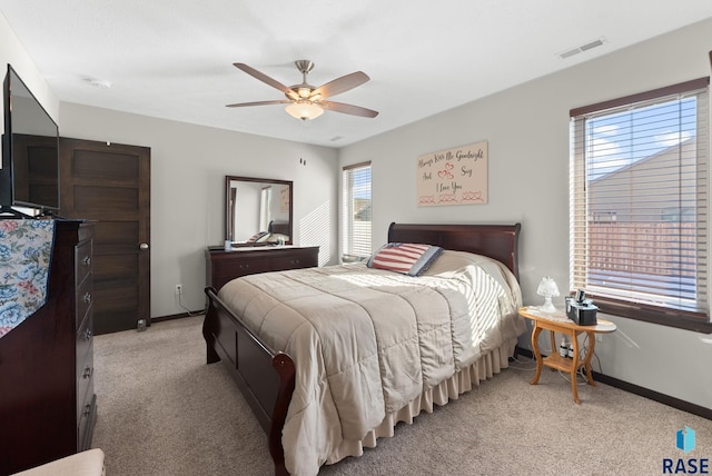 bedroom featuring visible vents, baseboards, a ceiling fan, and light colored carpet