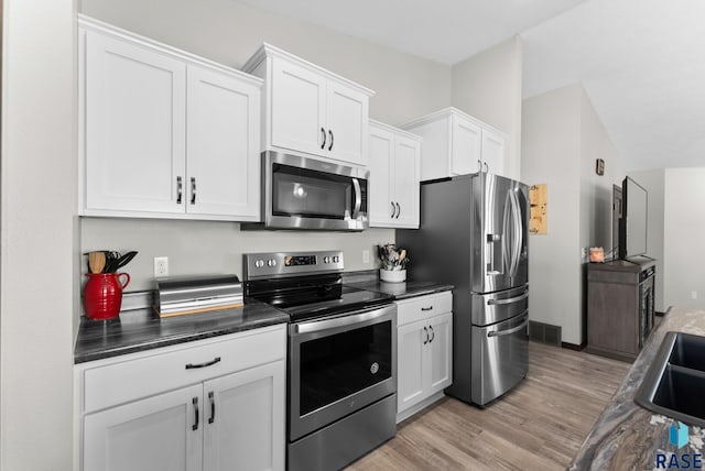 kitchen featuring stainless steel appliances, dark countertops, visible vents, and white cabinets