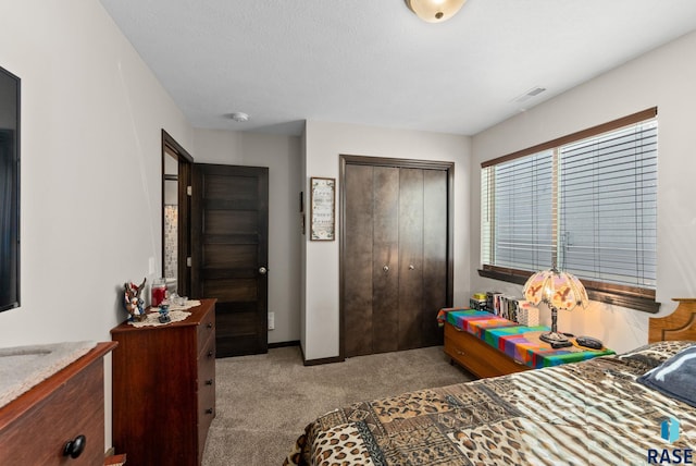 bedroom featuring a closet, light colored carpet, visible vents, a textured ceiling, and baseboards