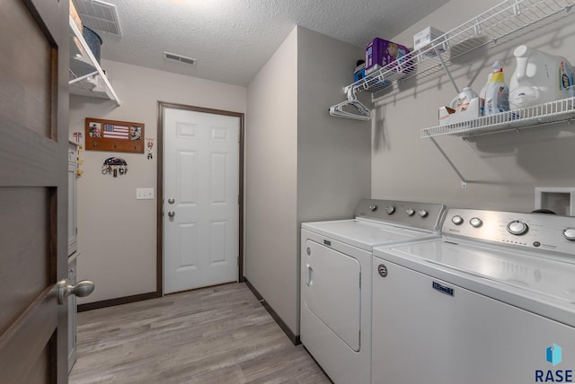 laundry area with light wood finished floors, visible vents, washing machine and dryer, a textured ceiling, and laundry area