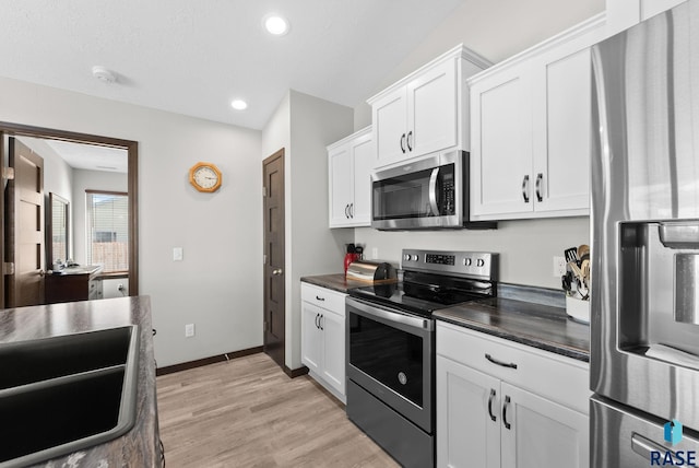 kitchen featuring appliances with stainless steel finishes, dark countertops, and white cabinets