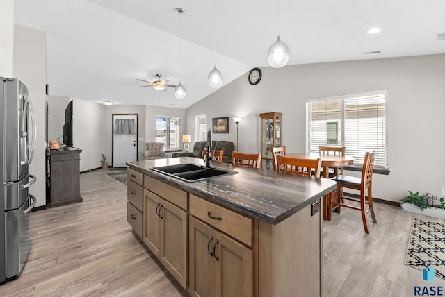 kitchen featuring dark countertops, freestanding refrigerator, open floor plan, a kitchen island, and a sink