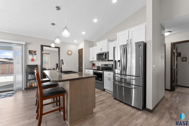 kitchen featuring appliances with stainless steel finishes, a breakfast bar, white cabinetry, and a center island with sink