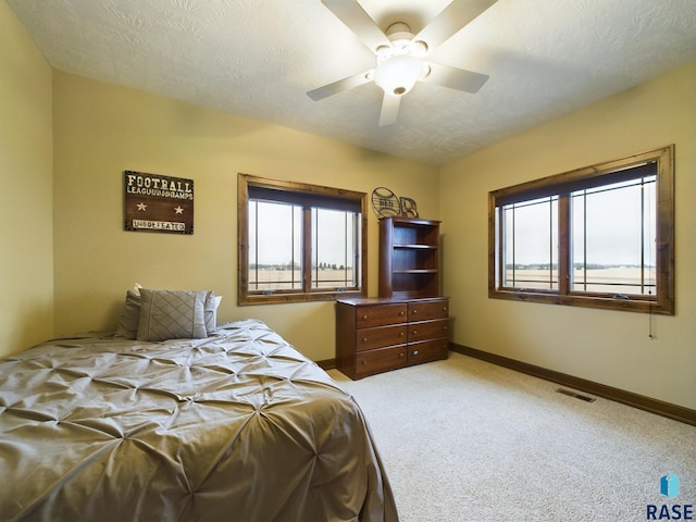 bedroom featuring light carpet, multiple windows, visible vents, and a textured ceiling