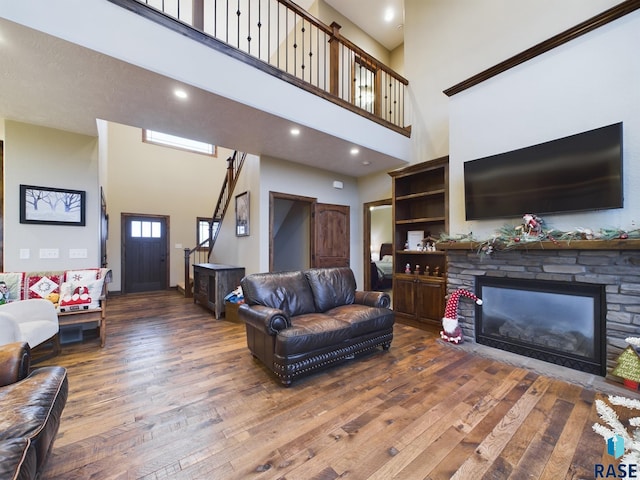 living area with a fireplace, a high ceiling, wood finished floors, and recessed lighting