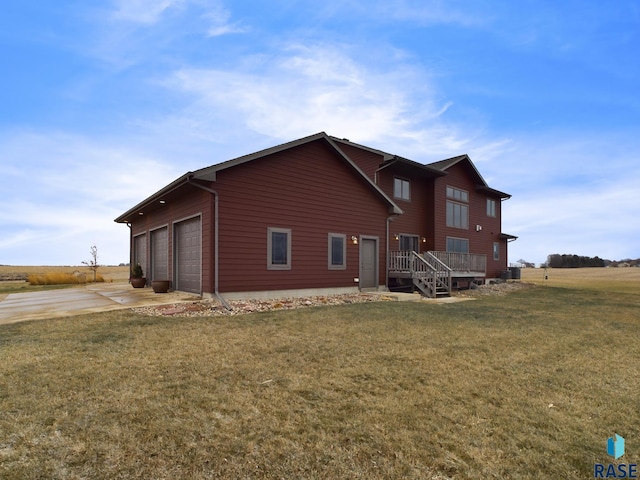 back of property with driveway, a garage, and a lawn