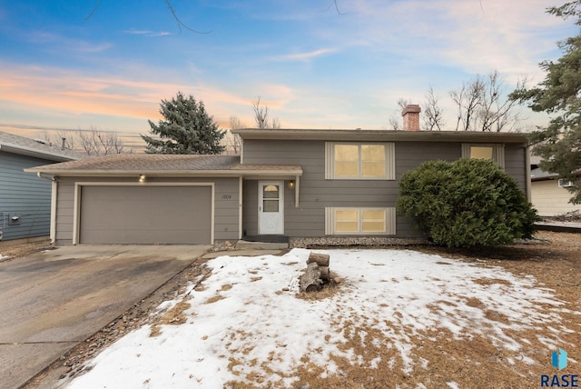 tri-level home featuring a garage, driveway, and a chimney