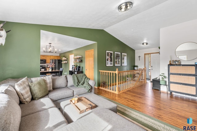 living area with lofted ceiling, a notable chandelier, and wood finished floors